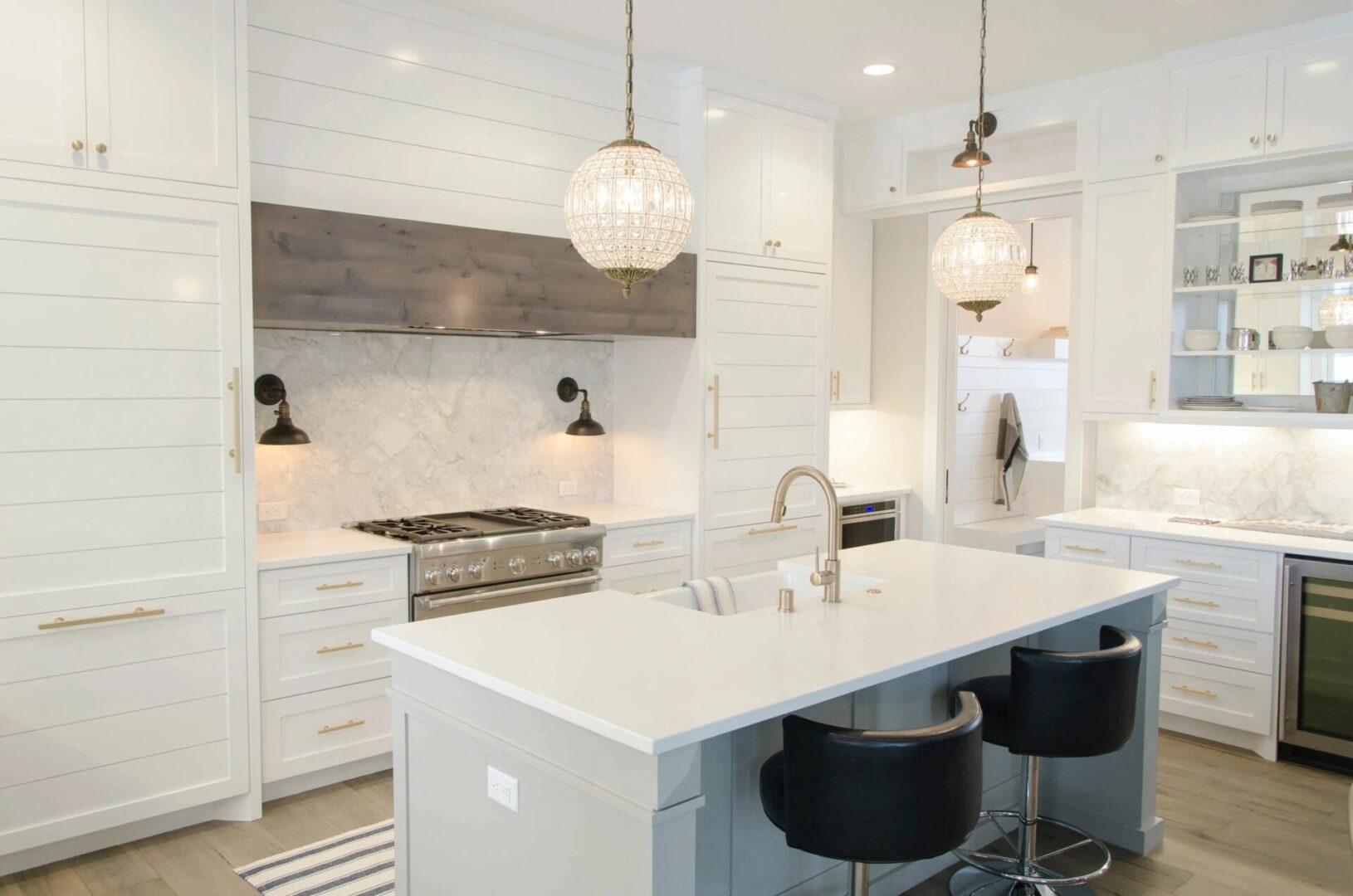 A kitchen with white cabinets and black stools.
